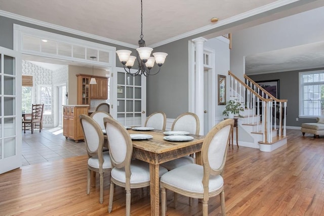 dining room with baseboards, a chandelier, light wood-style floors, ornamental molding, and stairs