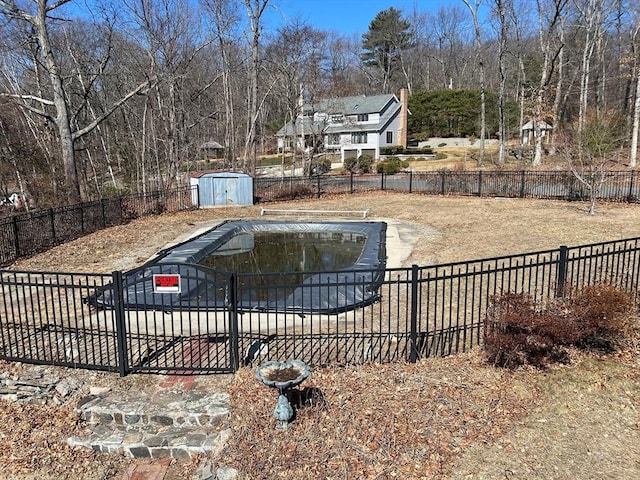 view of swimming pool featuring an outbuilding, fence, and a shed