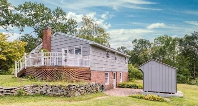 back of property with an outbuilding, a chimney, a deck, a storage shed, and a lawn