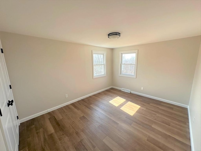 spare room with visible vents, baseboards, and wood finished floors