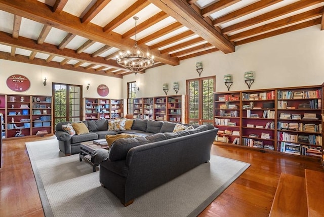 living room featuring an inviting chandelier, plenty of natural light, and beam ceiling