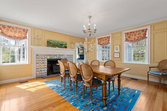 dining area featuring a notable chandelier, baseboards, visible vents, wood-type flooring, and a fireplace