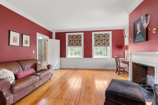 living area featuring a fireplace, crown molding, hardwood / wood-style flooring, and baseboards