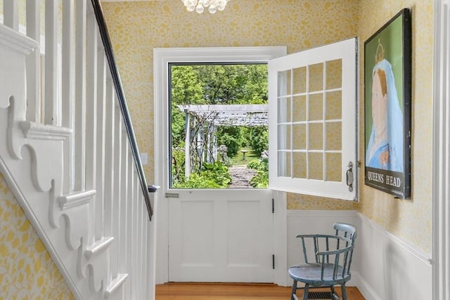 entryway featuring stairs, a wainscoted wall, wallpapered walls, and wood finished floors