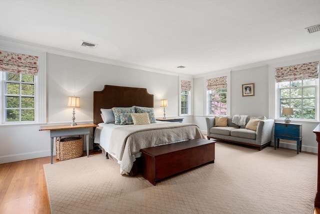 bedroom with ornamental molding, baseboards, light wood-style flooring, and visible vents