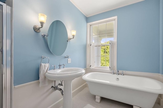 full bath featuring crown molding, tile patterned floors, baseboards, and a freestanding tub