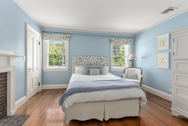 bedroom featuring ornamental molding, baseboards, visible vents, and wood finished floors