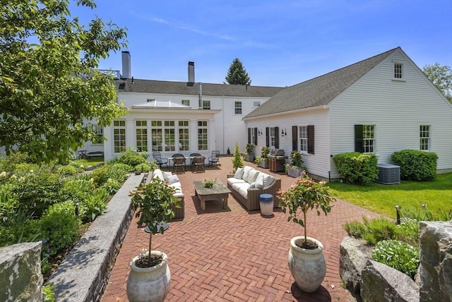 rear view of house featuring a patio, outdoor lounge area, cooling unit, and a shingled roof
