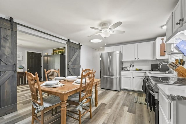 231 Georgetown Rd, Boxford, MA 01921 - kitchen with a barn door, appliances with stainless steel finishes, a sink, a ceiling fan, and light wood-type flooring