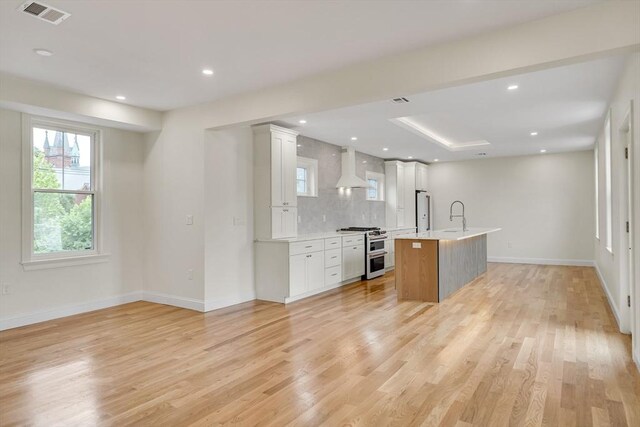 38 Green St Unit 38, Watertown, MA 02472 - kitchen featuring double oven range, light countertops, light wood-style flooring, a center island with sink, and tasteful backsplash