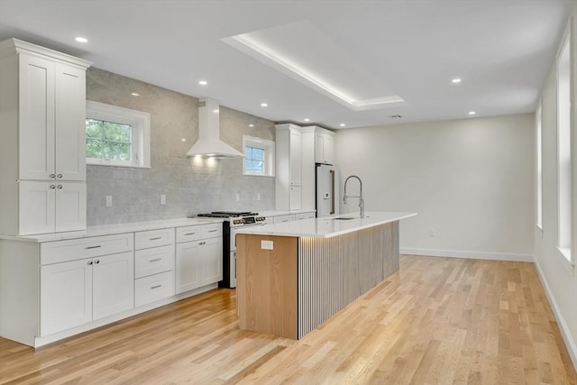 38 Green St Unit 38, Watertown, MA 02472 - kitchen featuring gas range, wall chimney exhaust hood, light wood finished floors, an island with sink, and backsplash