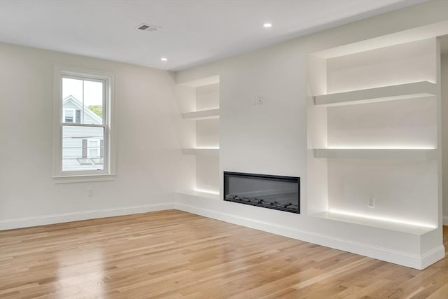 38 Green St Unit 38, Watertown, MA 02472 - unfurnished living room with light wood-style floors, a glass covered fireplace, baseboards, recessed lighting, and built in features