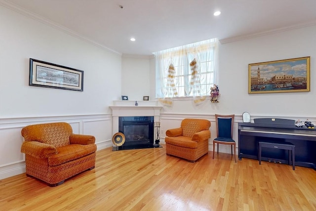 living area featuring a wainscoted wall, wood finished floors, and crown molding