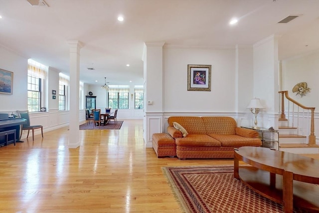 living room with light wood-style floors, decorative columns, visible vents, and a decorative wall