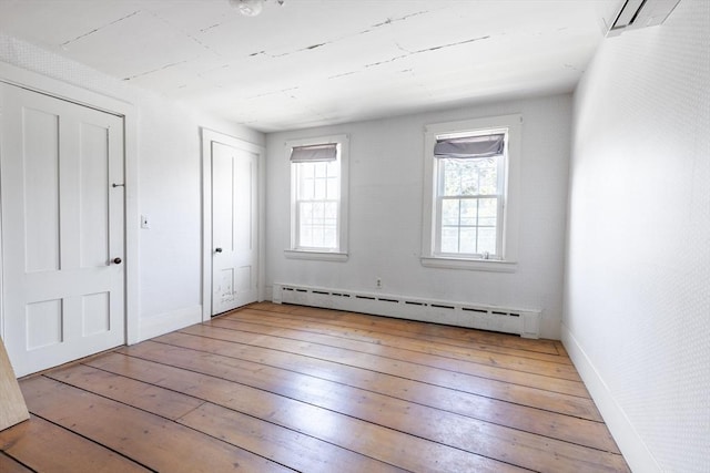 831 Main St, Dennis, MA 02638 - unfurnished bedroom with baseboard heating, wood-type flooring, an AC wall unit, and baseboards