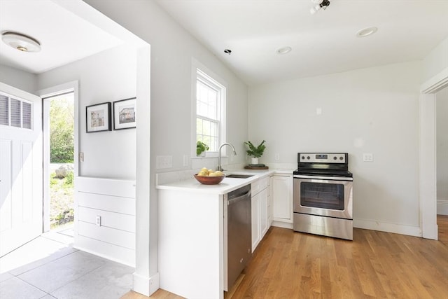 831 Main St, Dennis, MA 02638 - kitchen with stainless steel appliances, a sink, light countertops, white cabinets, and light wood finished floors