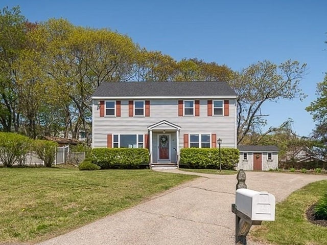 colonial inspired home featuring an outbuilding, a shed, and concrete driveway