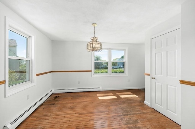 spare room with a baseboard radiator, hardwood / wood-style floors, a chandelier, and baseboards