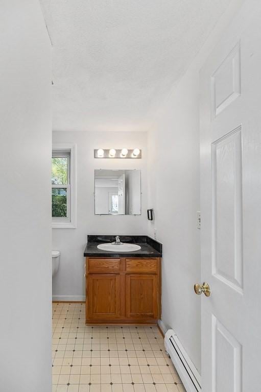 bathroom with tile patterned floors, baseboard heating, vanity, baseboards, and toilet
