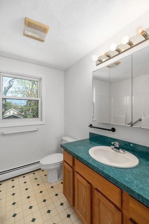 bathroom featuring a baseboard heating unit, vanity, and toilet