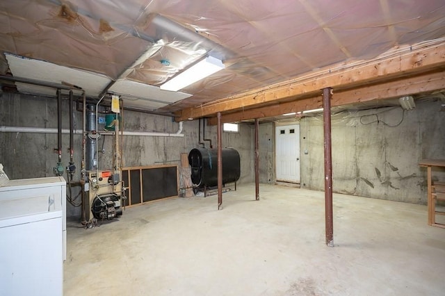 unfinished basement featuring oil tank, a heating unit, and washer and clothes dryer