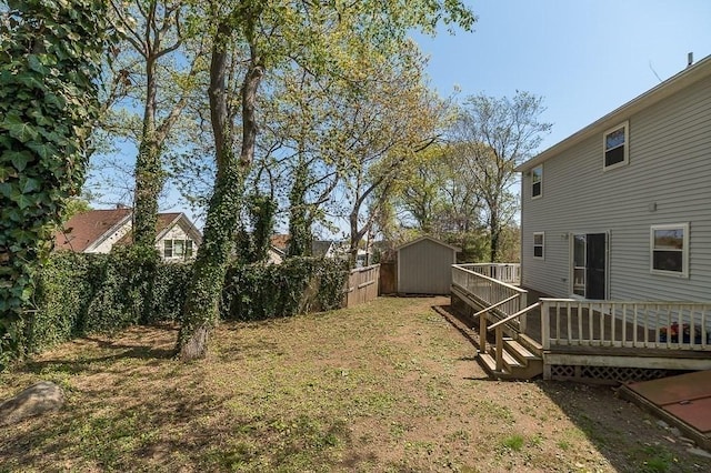 fenced backyard featuring a shed, a deck, and an outbuilding