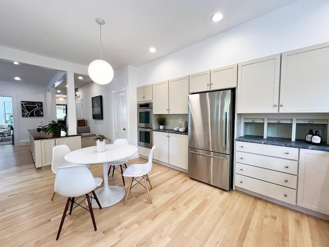 kitchen featuring appliances with stainless steel finishes, dark countertops, light wood-style flooring, and recessed lighting