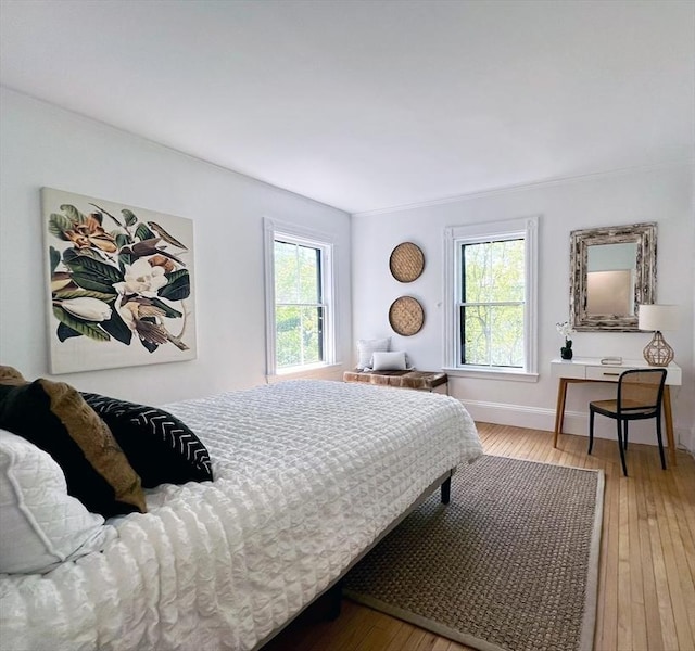 bedroom featuring light wood-type flooring, multiple windows, and baseboards