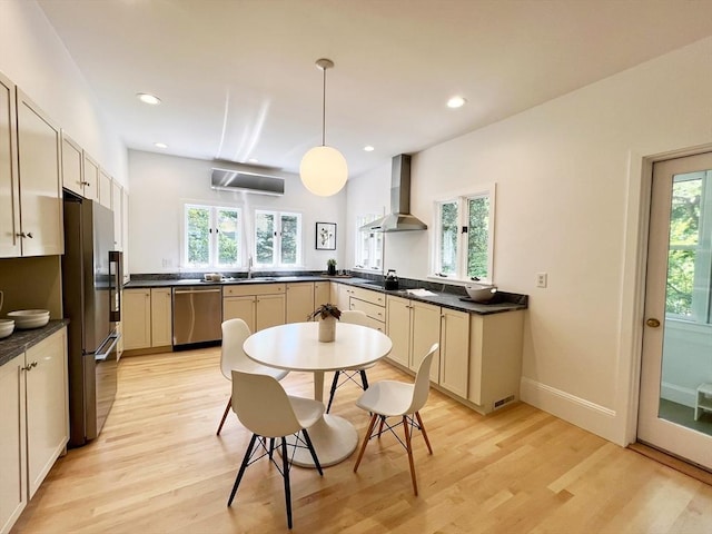 kitchen featuring wall chimney range hood, stainless steel appliances, light wood-type flooring, healthy amount of natural light, and recessed lighting
