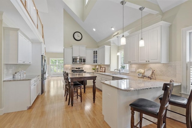 22 Hummock Way Unit 22, Hudson, MA 01749 - kitchen featuring appliances with stainless steel finishes, a peninsula, a sink, white cabinets, and high vaulted ceiling