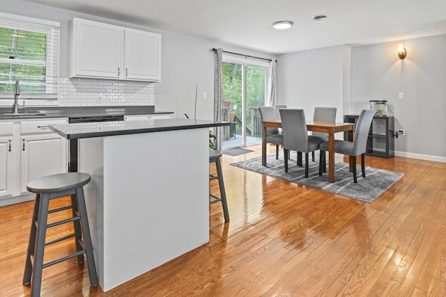 60 Mahogany Run Unit 60, Leominster, MA 01453 - kitchen with a sink, a breakfast bar, dark countertops, light wood finished floors, and white cabinetry