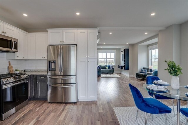 136 Flash Rd Townhome, Unit Townhome, Nahant, MA 01908 - kitchen with stainless steel appliances, plenty of natural light, light wood finished floors, and white cabinetry