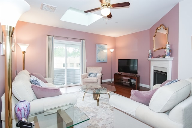 living room featuring ceiling fan, a skylight, and hardwood / wood-style floors