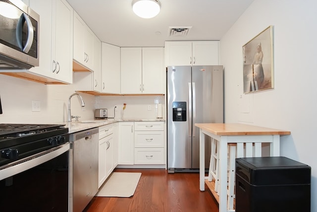 kitchen featuring white cabinets, light stone counters, appliances with stainless steel finishes, and dark hardwood / wood-style flooring