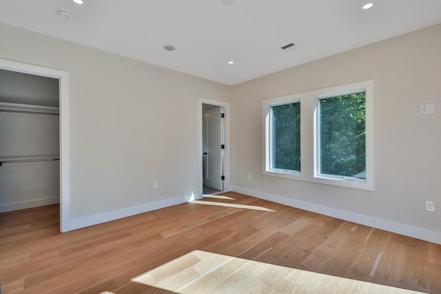 unfurnished bedroom with a walk in closet, light hardwood / wood-style floors, and a closet