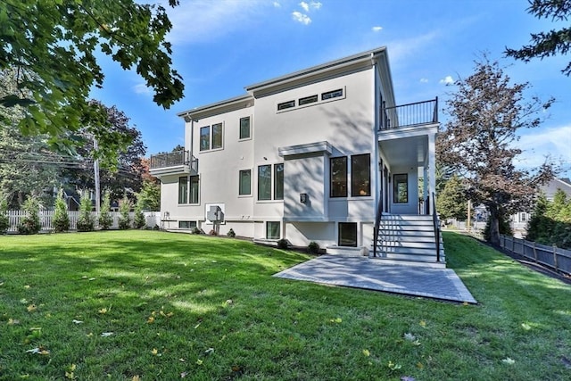 back of property featuring a balcony, a yard, and a patio area