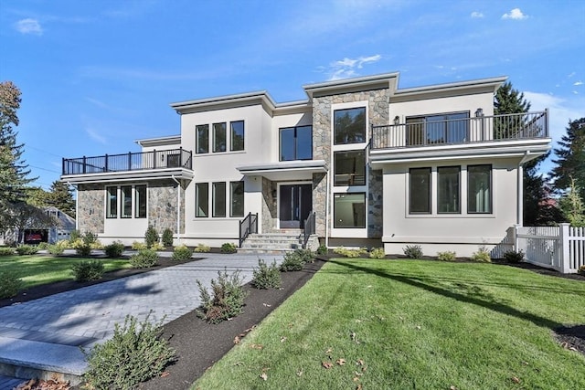 view of front of house featuring a balcony and a front lawn