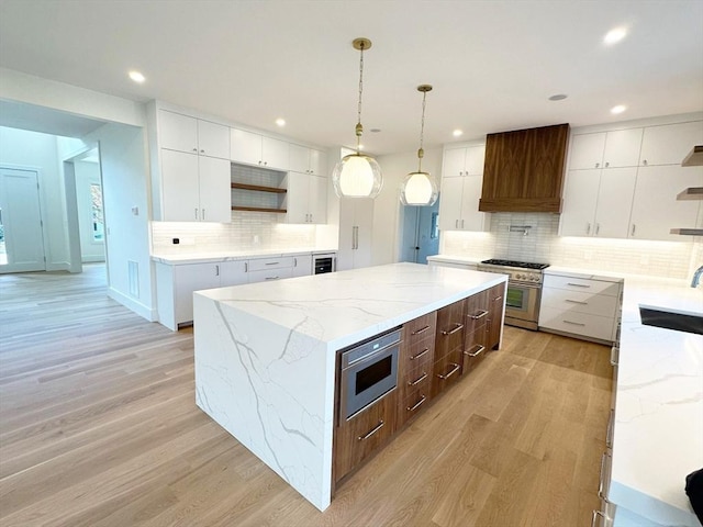 kitchen featuring stainless steel appliances, custom range hood, white cabinets, and a kitchen island