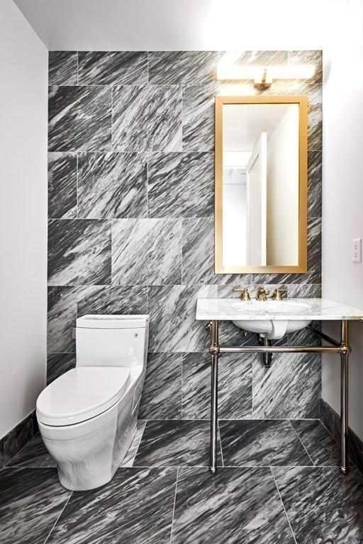 bathroom featuring toilet and tile walls