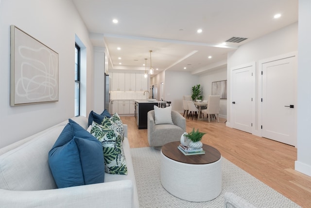 living room with light hardwood / wood-style flooring and sink