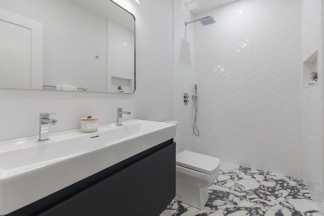 bathroom with toilet, vanity, and tiled shower