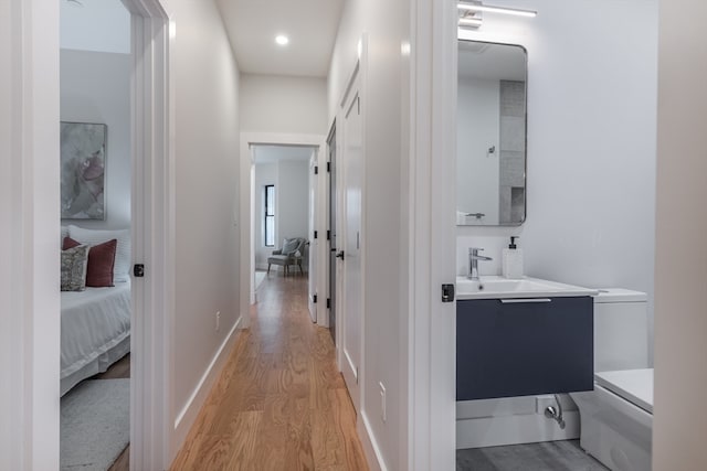 corridor with light wood-type flooring and sink