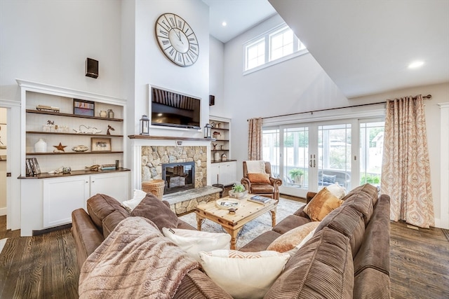 living room with french doors, dark hardwood / wood-style floors, a stone fireplace, and a high ceiling