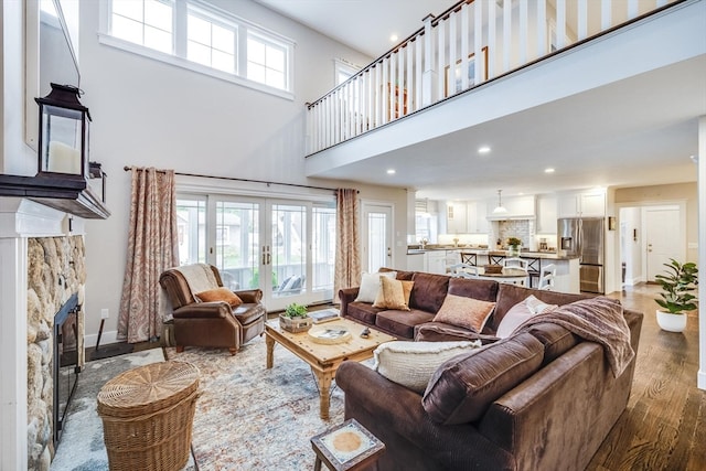 living room featuring a fireplace, a high ceiling, hardwood / wood-style flooring, and plenty of natural light