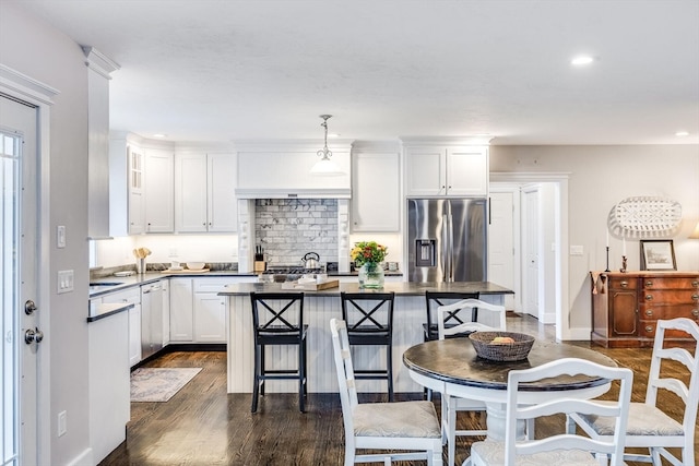 kitchen with decorative light fixtures, stainless steel fridge with ice dispenser, a center island, white cabinetry, and a breakfast bar area