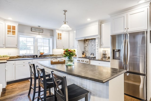 kitchen featuring appliances with stainless steel finishes, a breakfast bar, wood-type flooring, decorative light fixtures, and a kitchen island