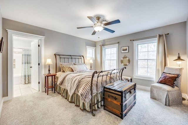 bedroom with connected bathroom, light colored carpet, and ceiling fan