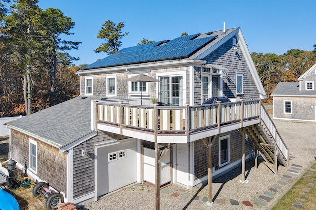 rear view of property with solar panels, a garage, and a wooden deck