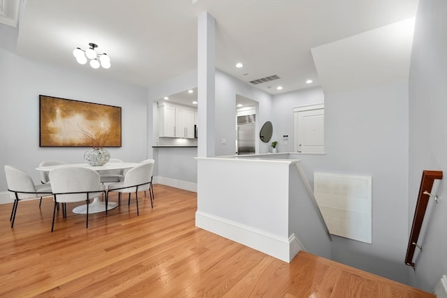 kitchen with white cabinetry, light wood-type flooring, and kitchen peninsula