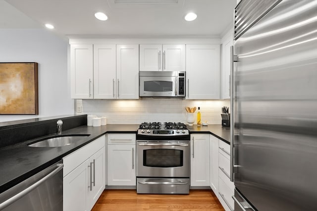 kitchen with sink, white cabinets, stainless steel appliances, and light hardwood / wood-style floors